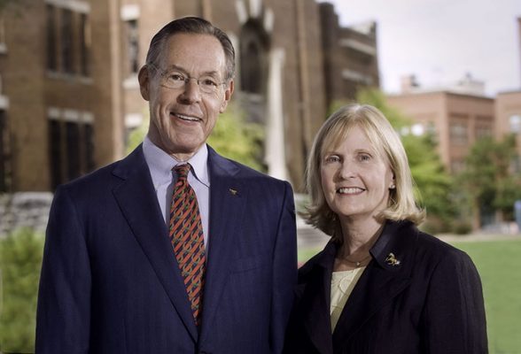 Eric and Judith Mower wearing dark suits standing outside on SU campus